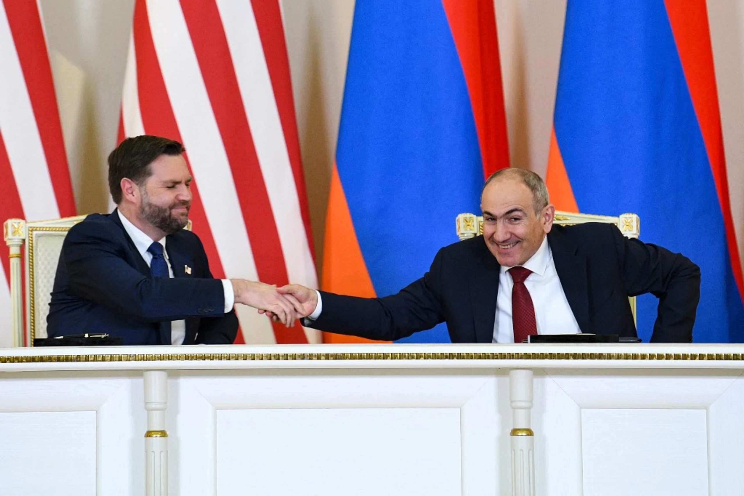 Володимир Зеленський і Нікол Пашинян тиснуть руки на тлі прапорів країн