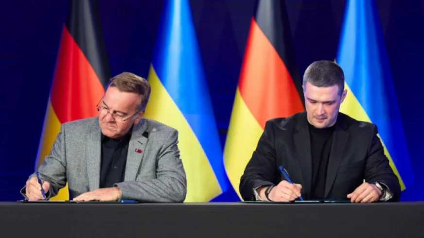 Борис Пісторіус і Рустем Умєров підписують угоду під прапорами Німеччини та України
