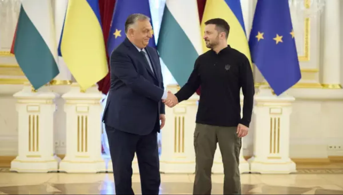 Володимир Зеленський потискає руку Віктору Орбану перед прапорами України, Угорщини та ЄС.