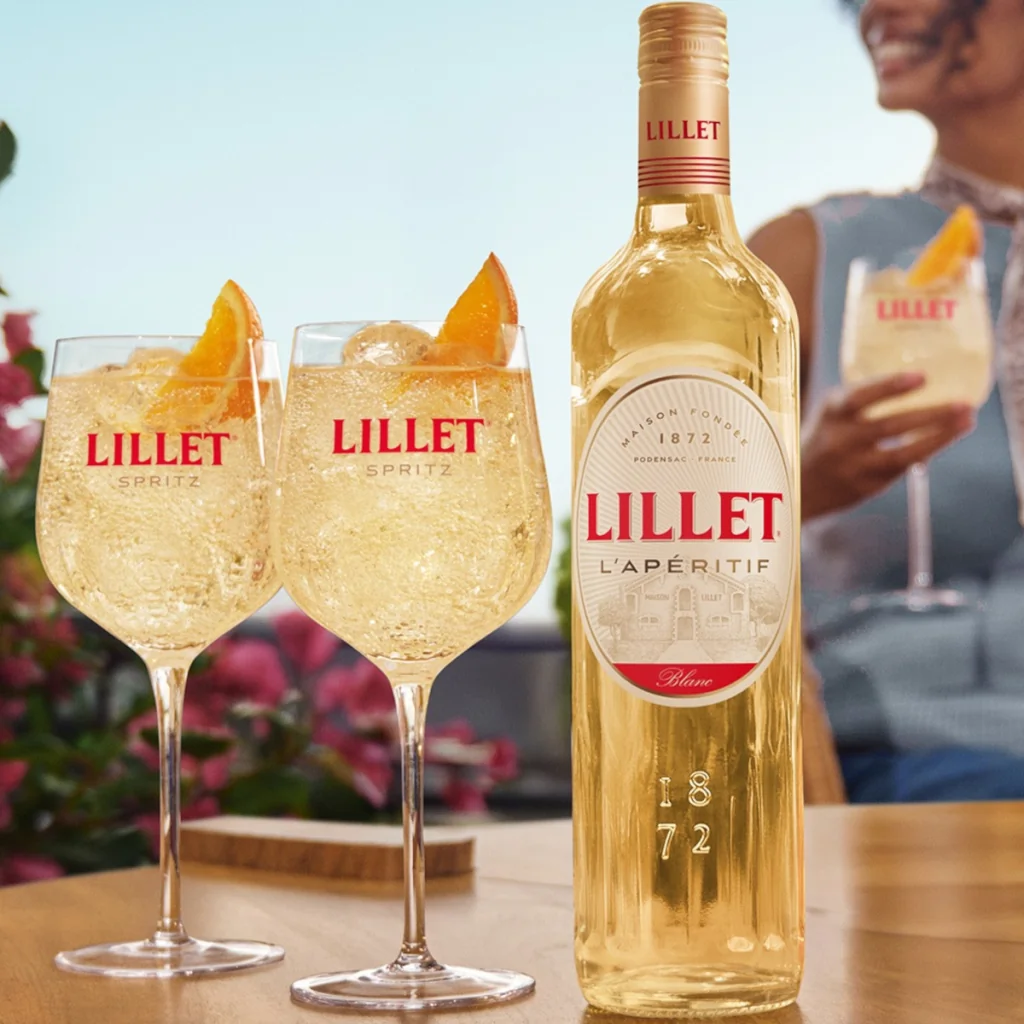 Бутылка Lillet и два бокала Lillet Spritz с апельсином на столе