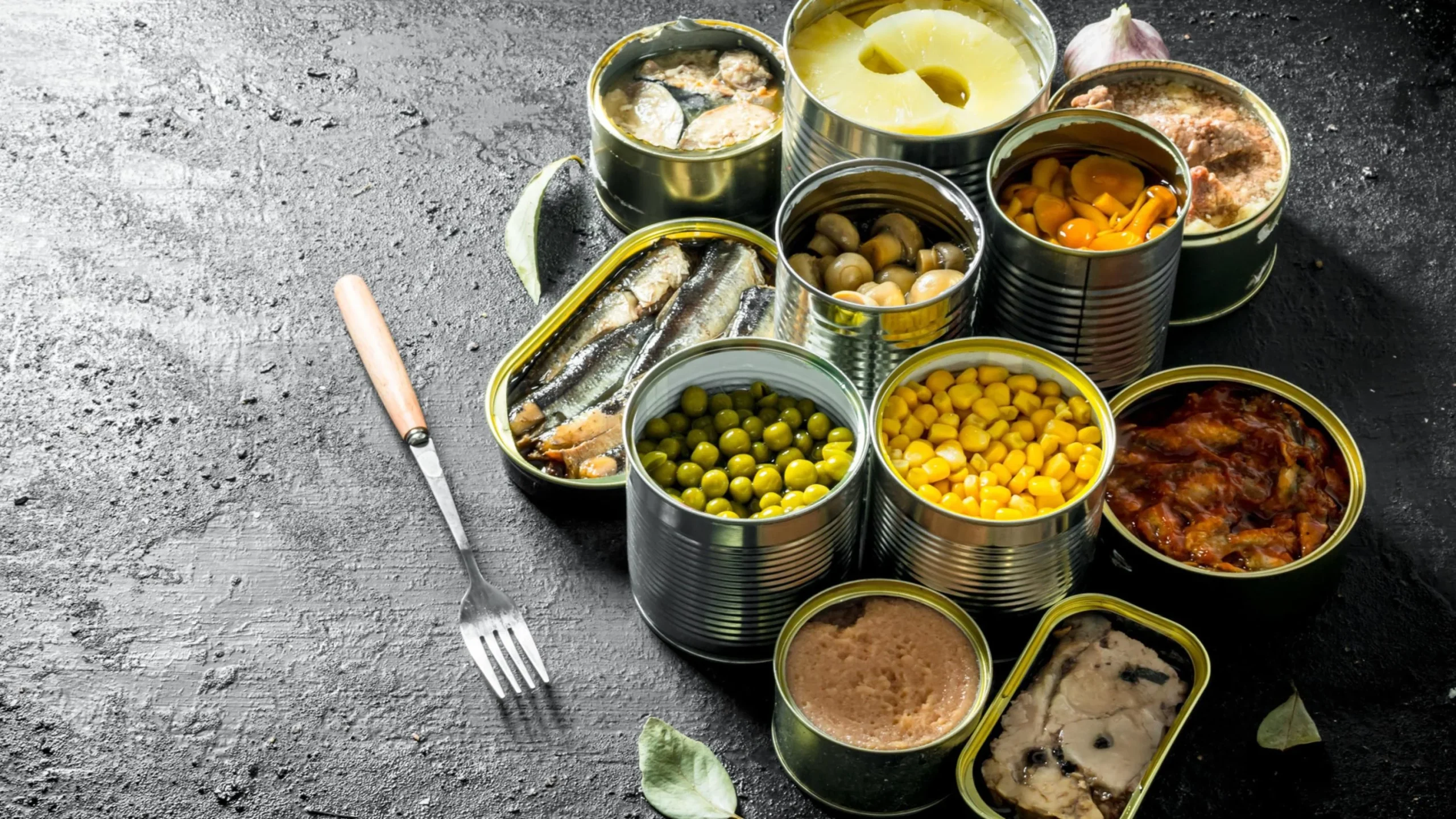 Відкриті банки консервів з рибою, овочами та мясом на столі