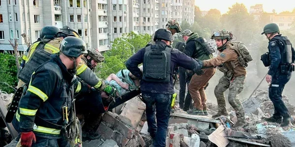 Рятувальники виносять пораненого на ношах після удару по будинку в Харкові